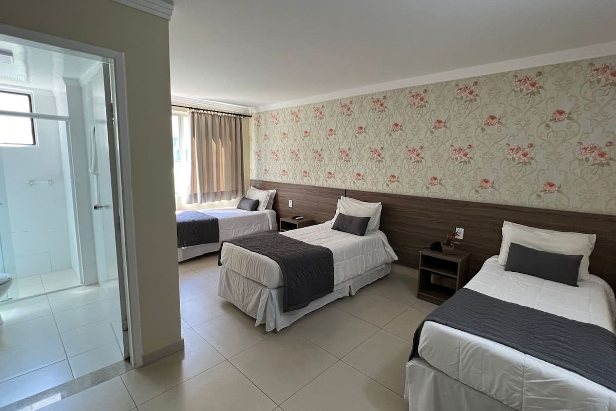 A hotel room with two beds, a shower area, and a bathroom.