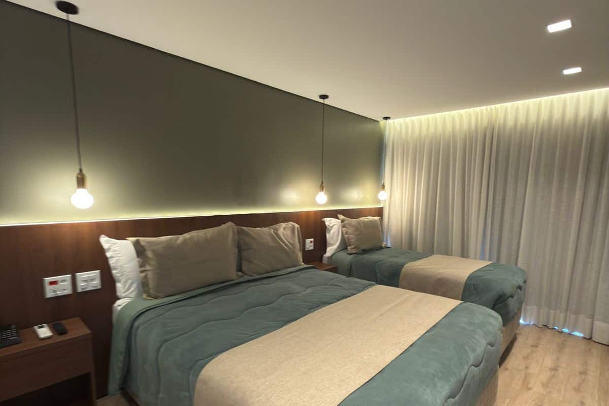 A modern hotel room with a large bed, bedside tables, a nightstand, and a curtain.