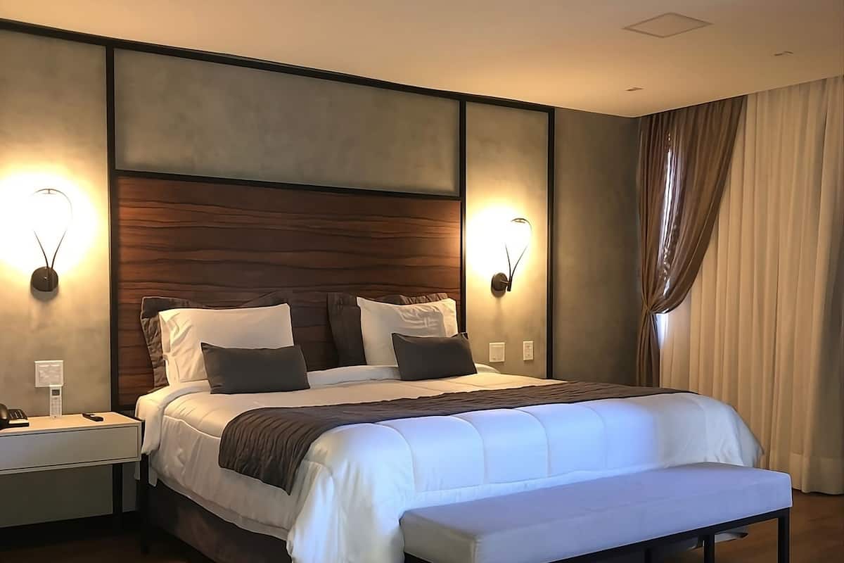 A modern bedroom with a large bed, bedside tables, and wall-mounted lighting.