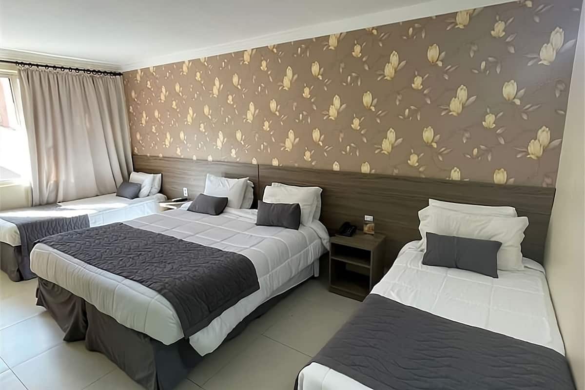 A hotel room with two beds, a nightstand, and a window with curtains.