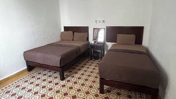 Un dormitorio con dos camas, ventilador de techo y suelo estampado.