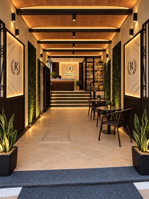 Un vestíbulo de hotel con mostrador de recepción, zona de estar y una escalera que lleva a los pisos superiores.