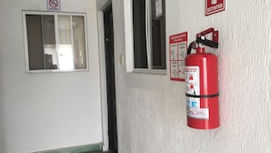 A hallway with a fire extinguisher mounted on the wall, a 'No Smoking' sign, and a door with a window. - Suites Ripoll Córdoba (Córdoba)