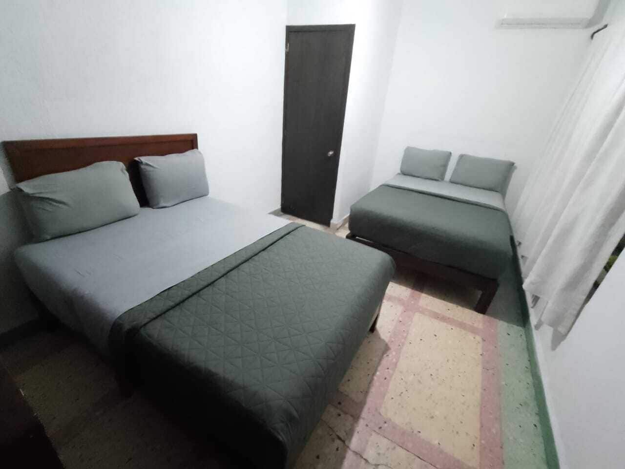 Une petite pièce simple, avec un lit, un canapé et une porte.