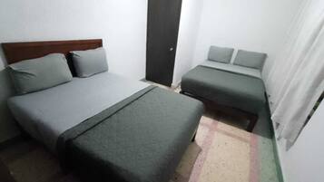 Une petite pièce simple, avec un lit, un canapé et une porte.