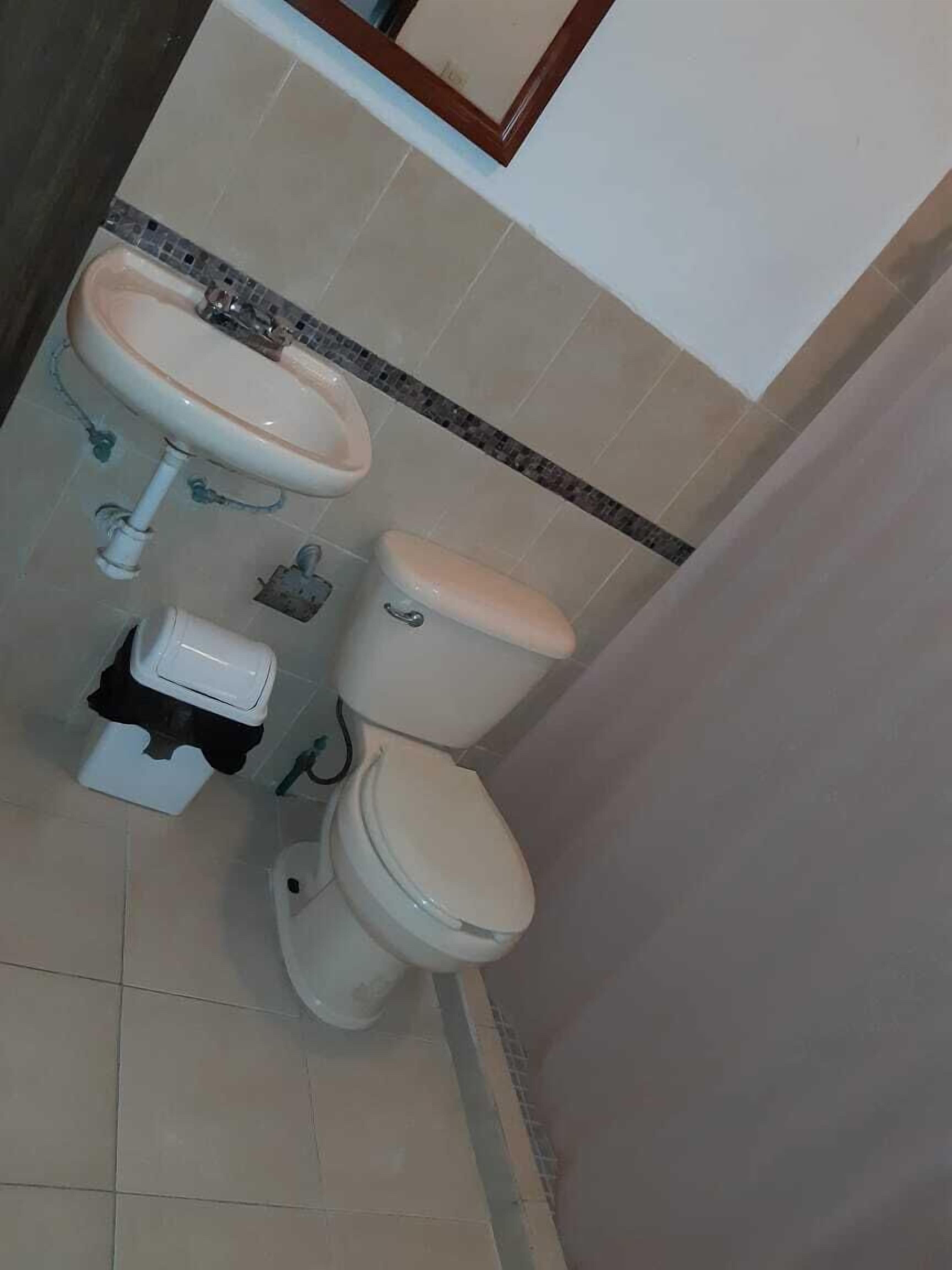 A bathroom with a toilet, sink, and a trash bin.
