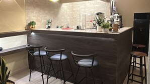 Eine moderne Küche mit Barbereich, Barhocker und Pendelleuchten.