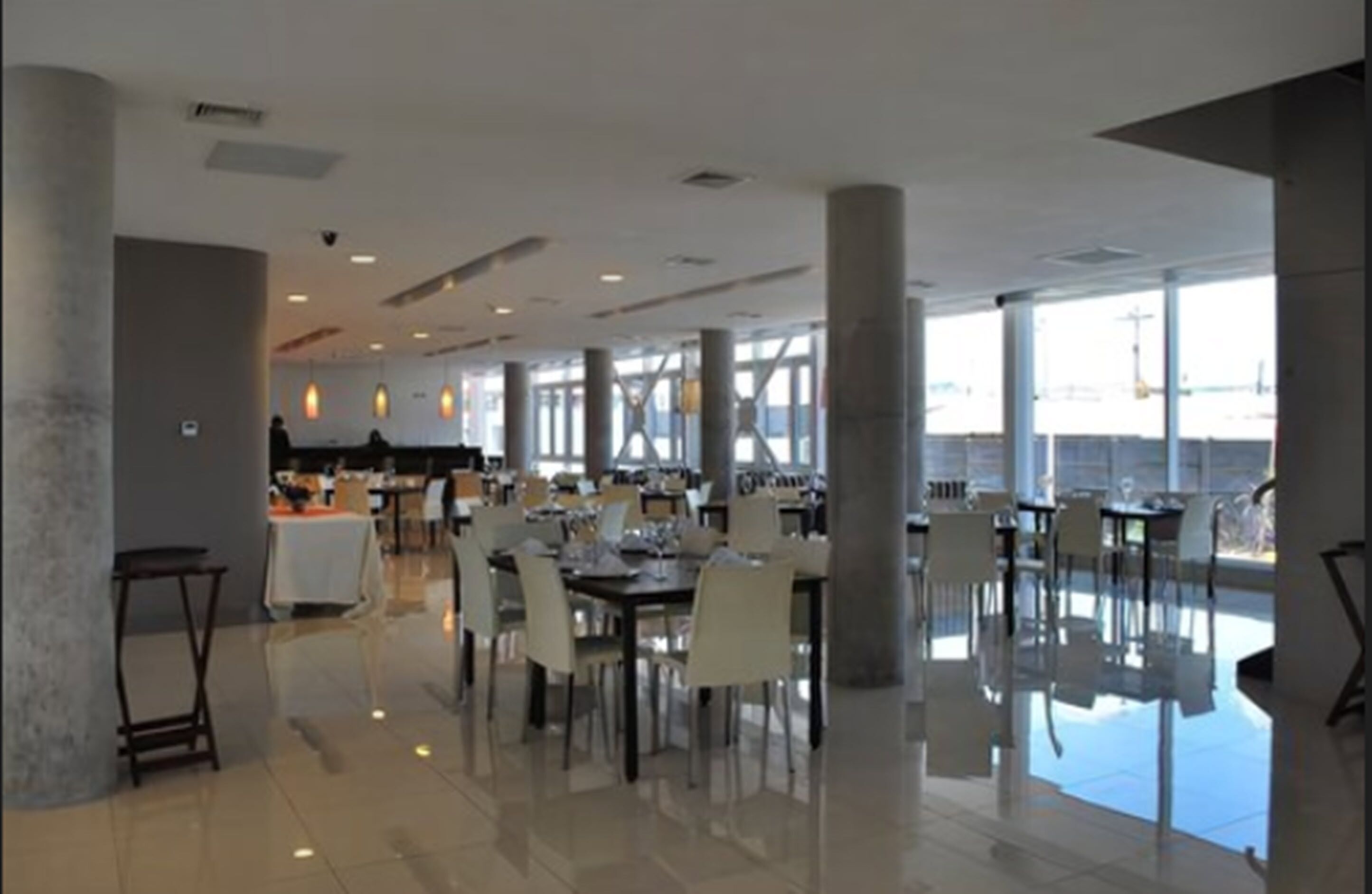 Un comedor amplio con techos altos, ventanas grandes y muebles modernos.