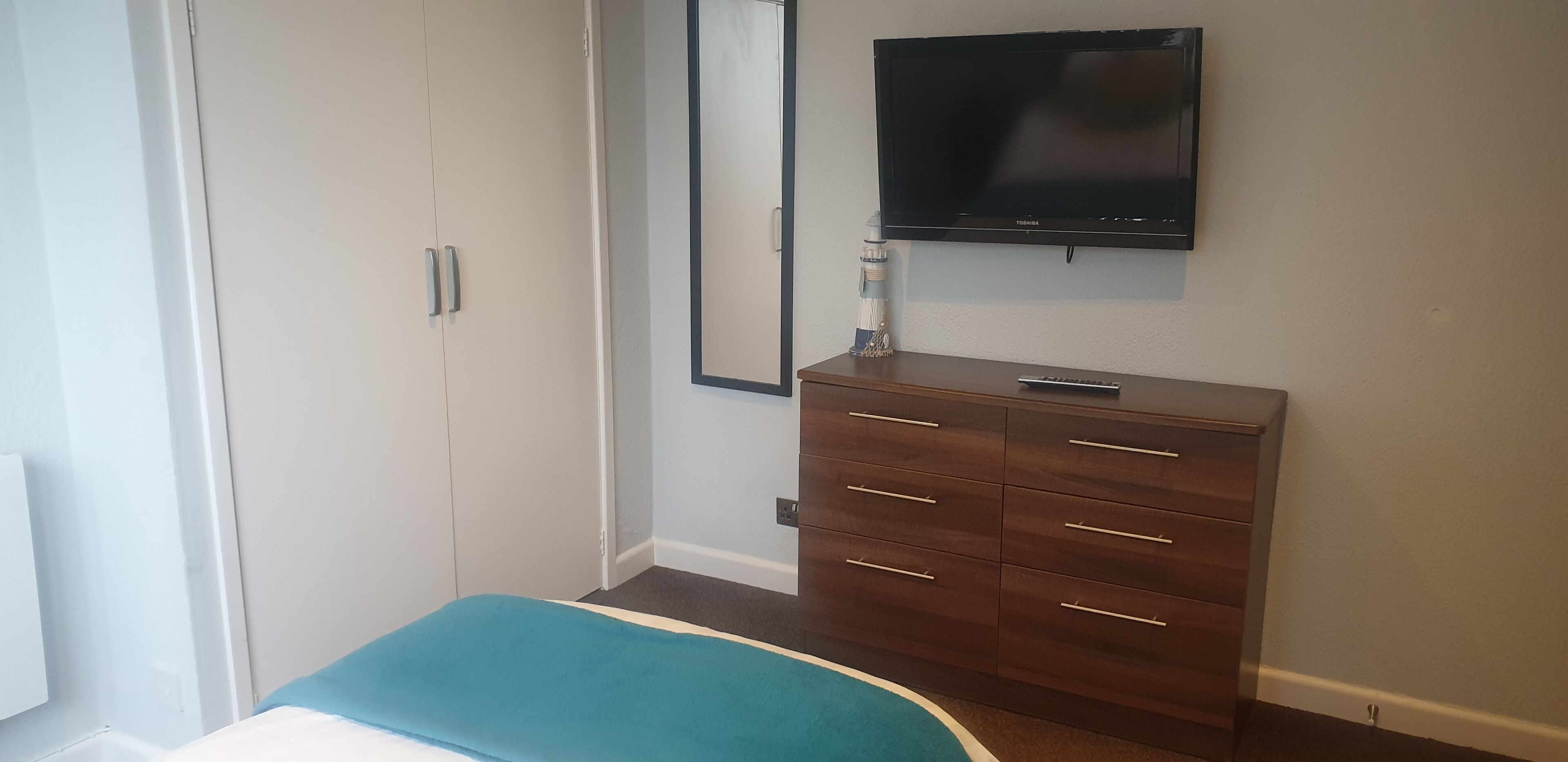 A bedroom with a bed, a dresser, a television, and a wardrobe.