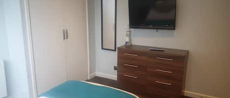 A bedroom with a bed, a dresser, a television, and a wardrobe.