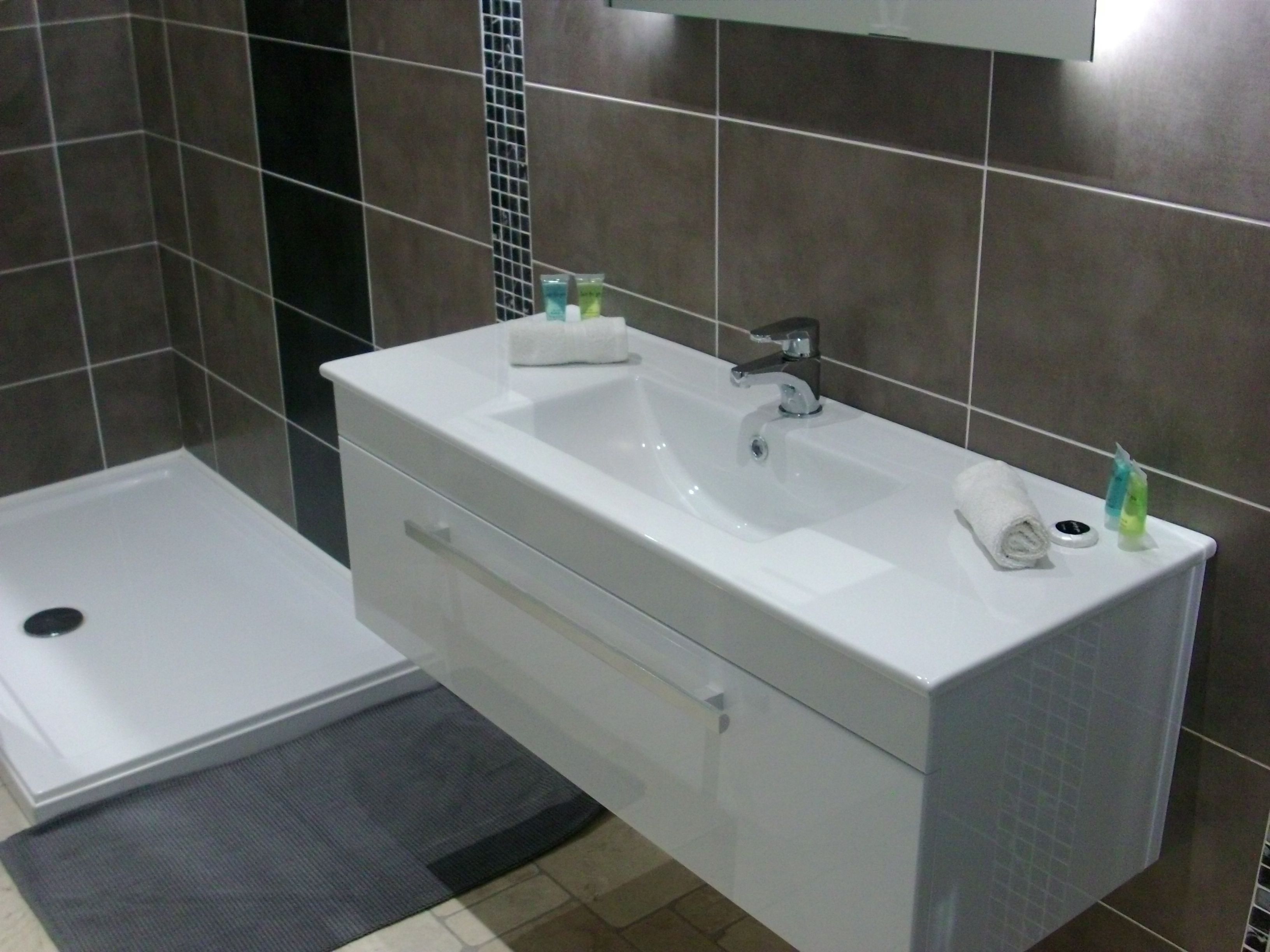 A modern bathroom with a white sink, a mirror, and a shower area.