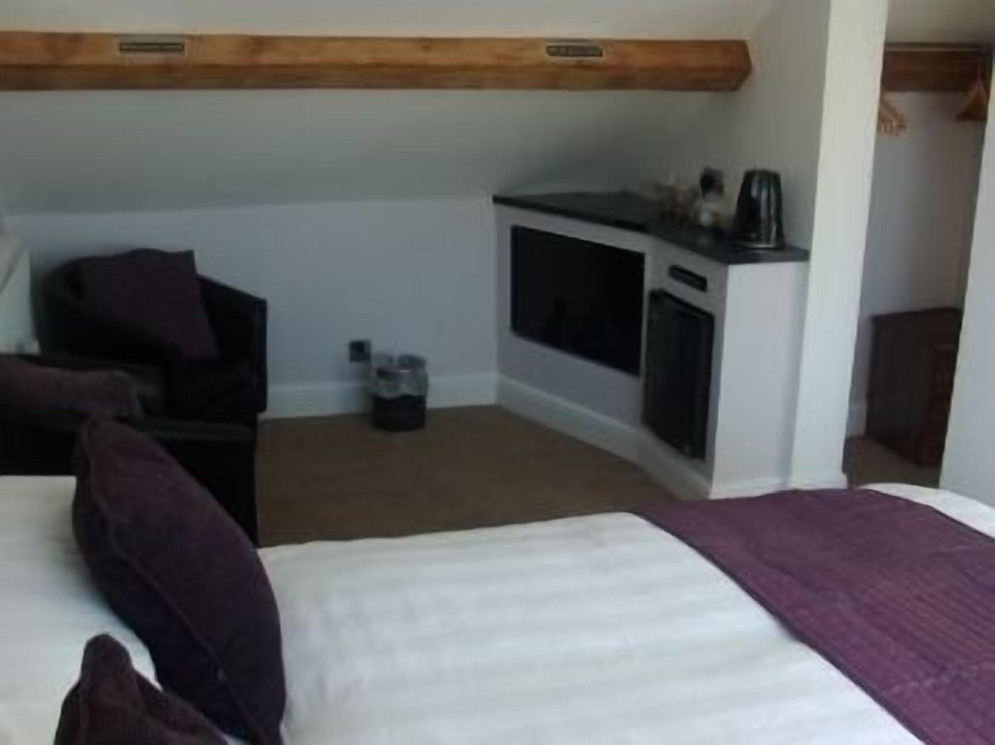 A hotel room with a bed, a small kitchenette, and a seating area.