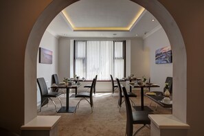 A conference room with a high ceiling, recessed lighting, and large windows with blinds. - Farnham Hotel (Tenby)