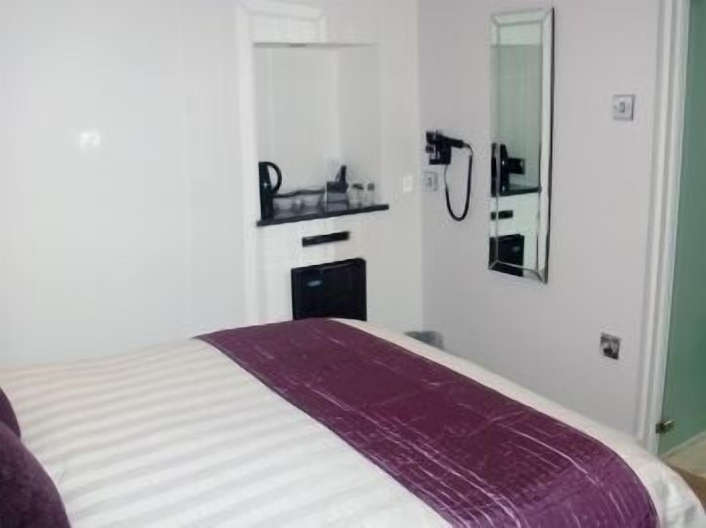 Una habitación de hotel con cama, un escritorio pequeño con espejo y zona de ducha.