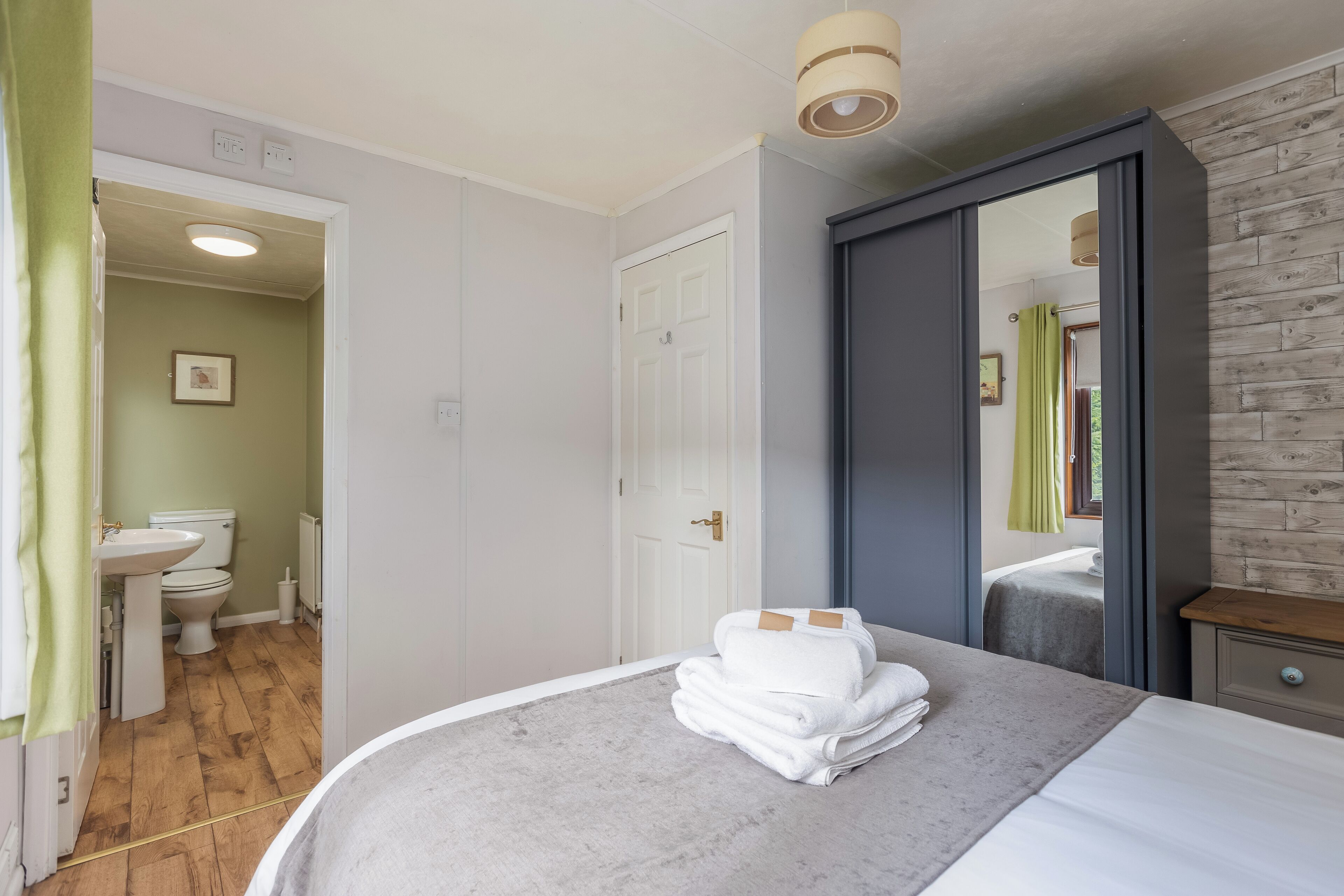 Une chambre d’hôtel comprenant un lit, une salle de bain avec des toilettes et un lavabo, ainsi qu’un miroir.