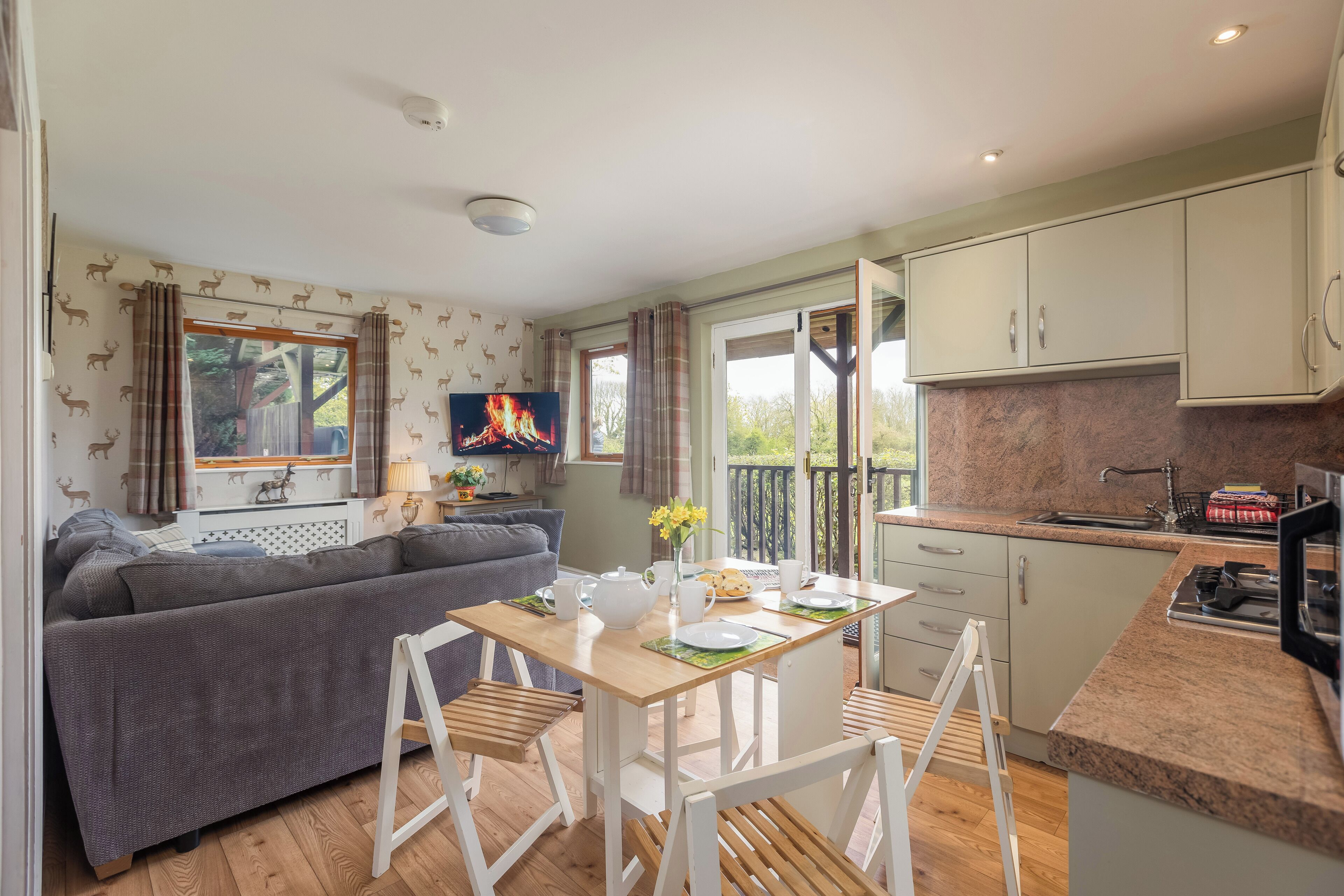 A cozy living area with a sofa, a dining table with chairs, a kitchen with cabinets, and a TV.