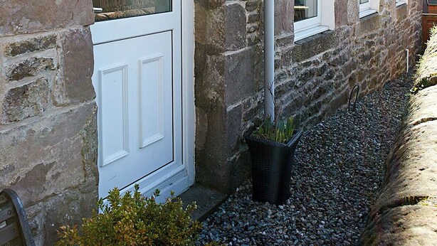 A stone building with white-framed windows, a visible pipe, and a gravel pathway. - Crieff Armoury Luxury Self Catering Apartment (Crieff)