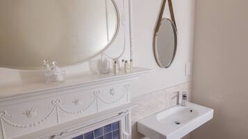Un baño con tocador blanco, un espejo grande, un lavamanos y un panel decorativo en la pared.