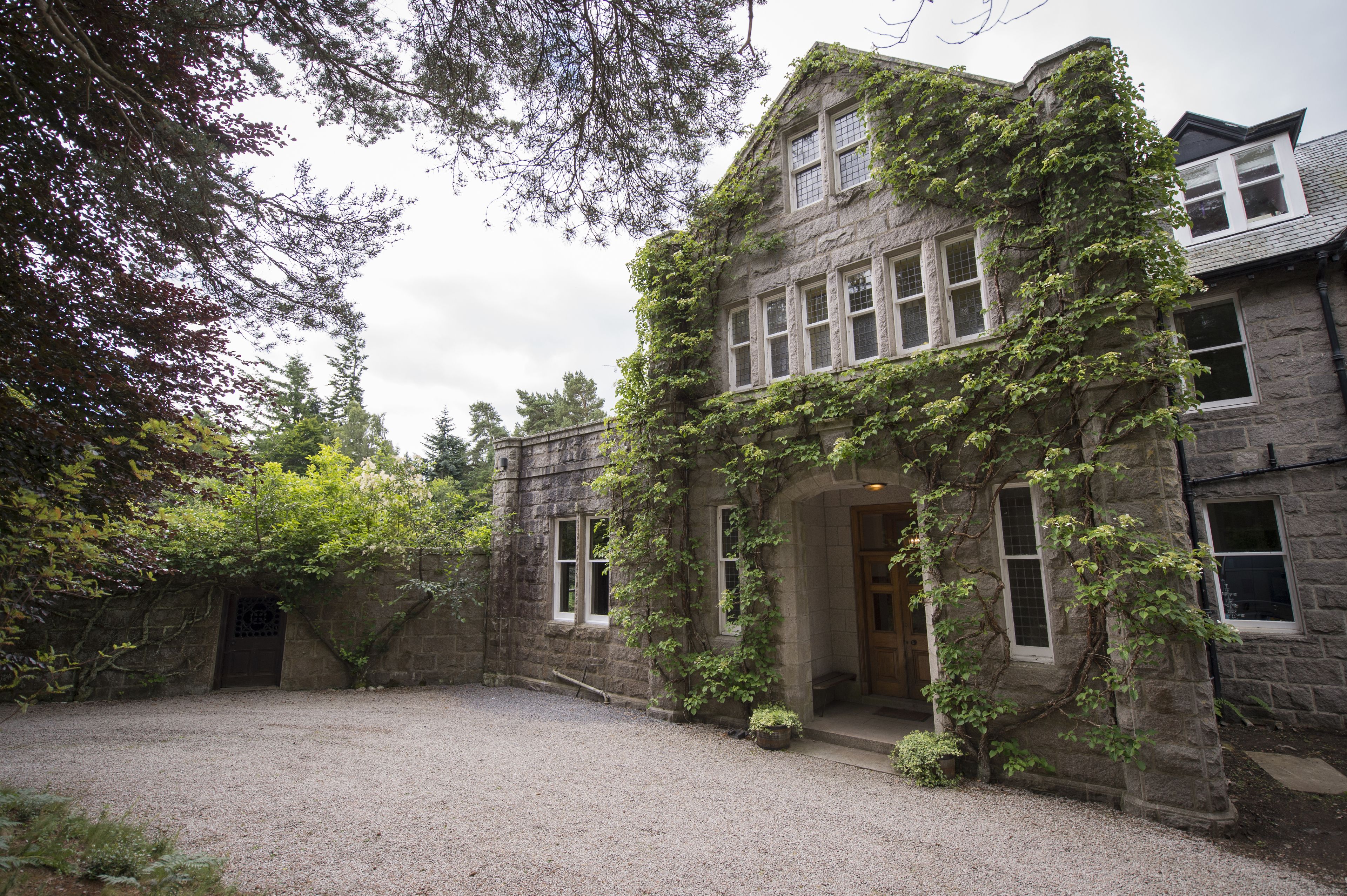 A historic stone building with ivy-covered walls and a gravel courtyard.