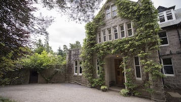 A historic stone building with ivy-covered walls and a gravel courtyard.