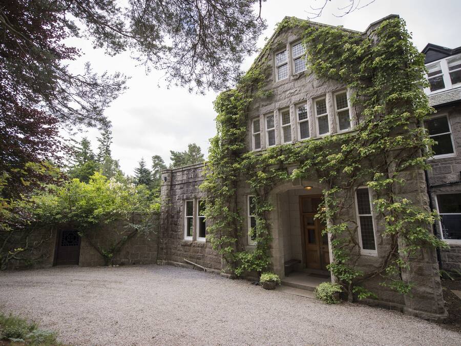 A historic stone building with ivy-covered walls and a gravel courtyard.