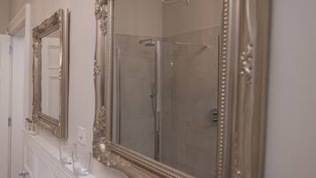 Un baño con dos espejos decorativos, un lavamanos y una ducha.