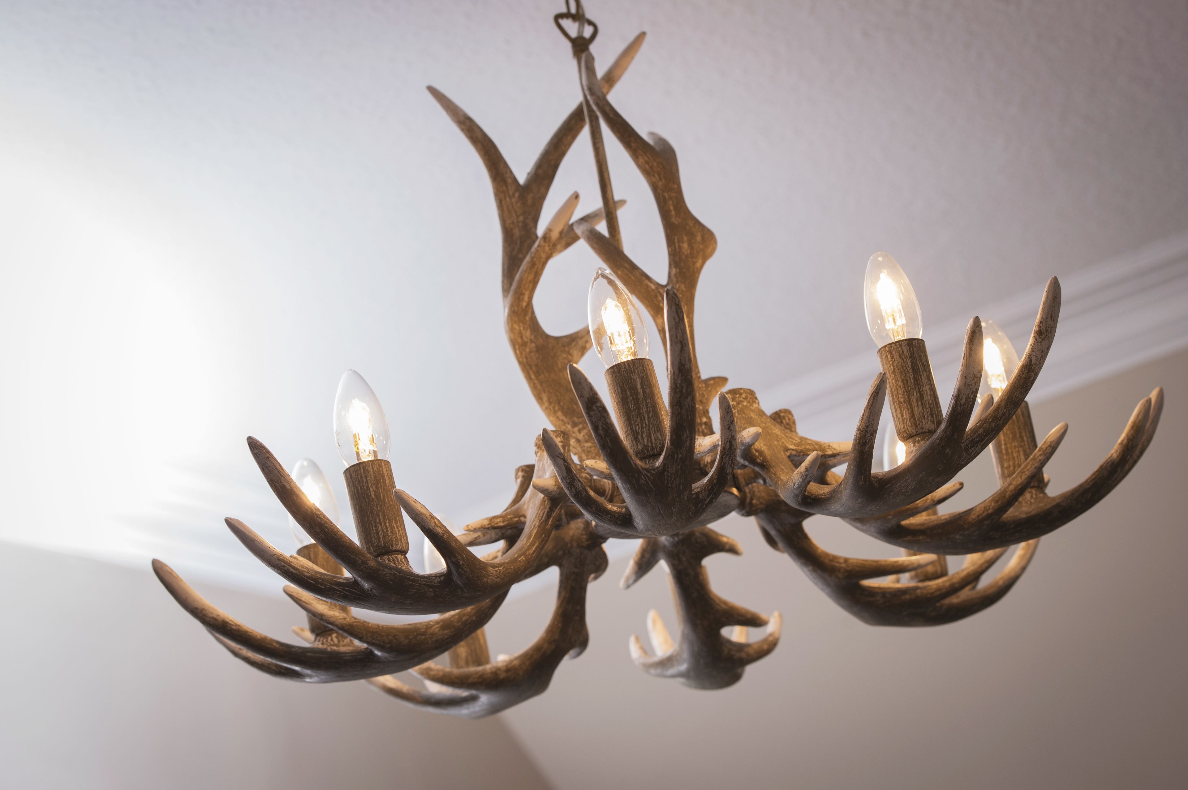 A chandelier with antler-shaped metal arms and light bulbs.
