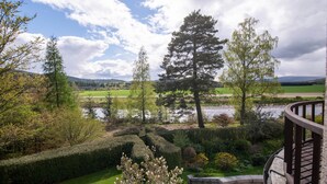 A landscaped garden with a stone pathway, neatly trimmed hedges, and a variety of trees. - Lys-Na-Greyne Country House (Aboyne)