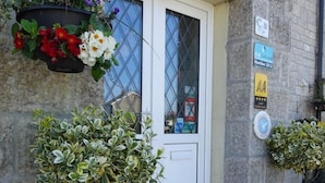 A stone building with a white door, a sign reading "Charlestone," and various signs including "Visit Cornwall Member 2012" and "AA Quality." - Thurlestone Guest House (St Ives)
