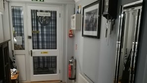 A hallway with a fire exit sign, a door labeled "VACANCIES", a fire extinguisher, a radiator, and a mirror. - Thurlestone Guest House (St Ives)