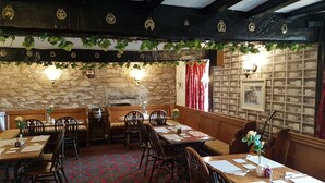 Une auberge traditionnelle aux murs de pierre, aux bancs en bois et au tapis à motifs.