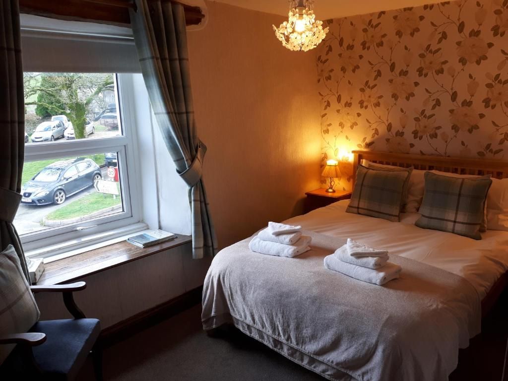 A hotel room with a bed, a nightstand, a lamp, a window with curtains, and a view of the outside.