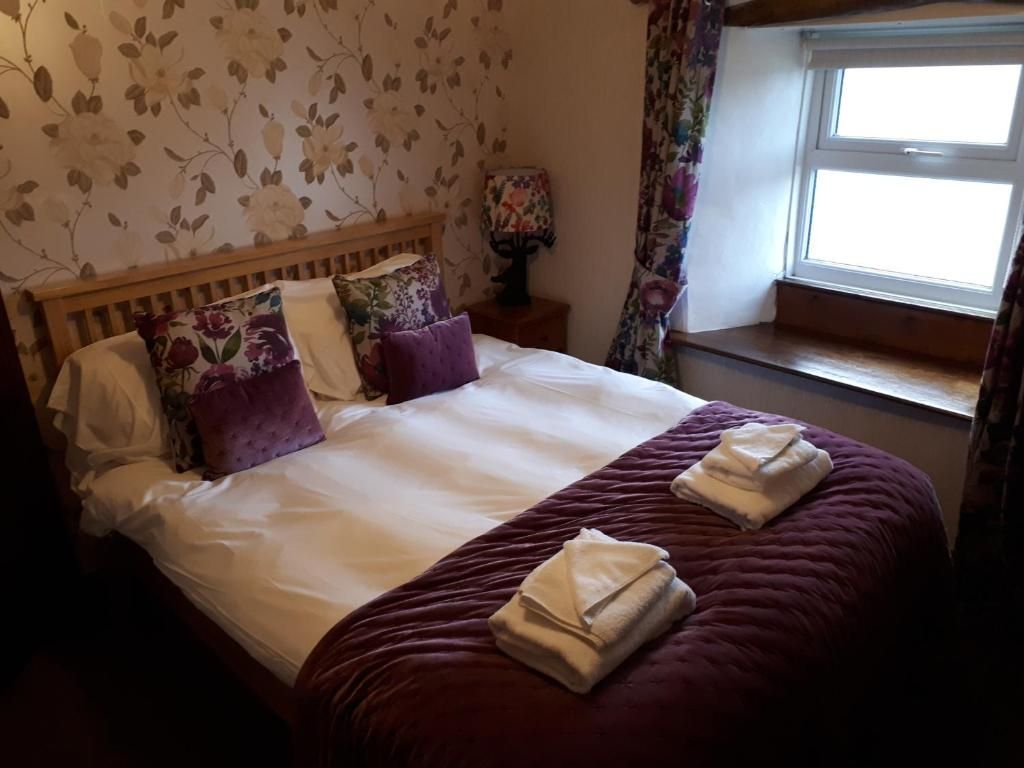 Une chambre d’hôtel avec un lit, un papier peint à motifs floraux, une fenêtre avec des rideaux et une table de chevet avec une lampe.