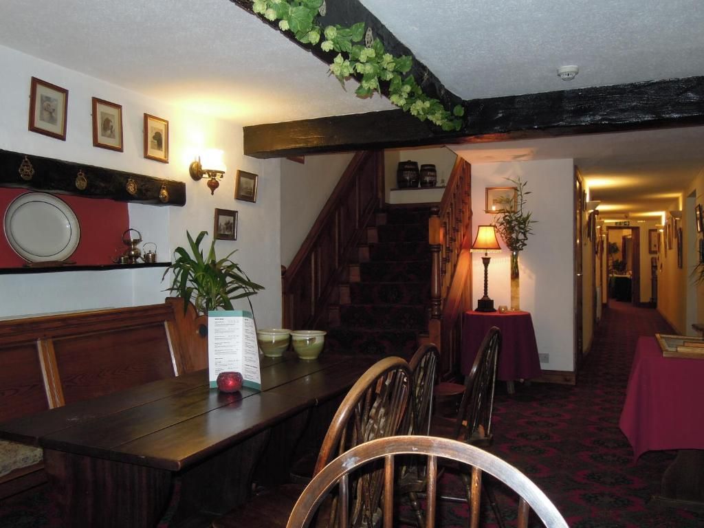 A dining area with a wooden table and chairs, a staircase, and a hallway with a carpeted floor.