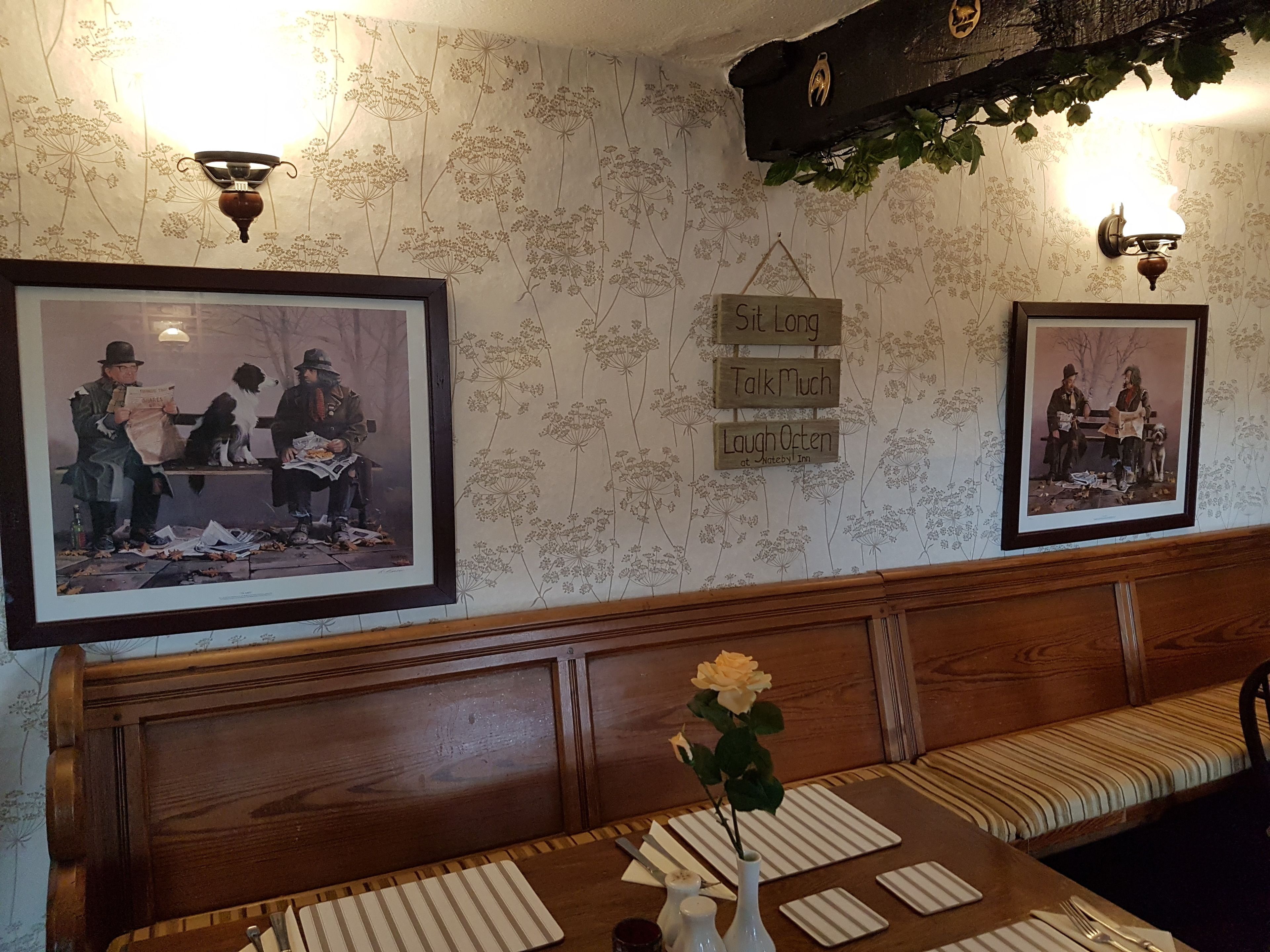 Un rincón acogedor con bancos de madera y una mesa con un jarrón de flores.