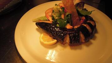 A plate with grilled fish, vegetables, and a lemon wedge.
