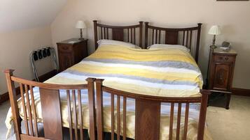 A bedroom with a wooden four-poster bed, two bedside tables, a nightstand, and a chair.