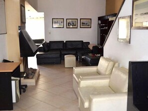 A living room with a black sofa set, a white sofa, a TV, and a fireplace.