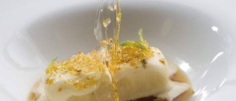 A white plate with a dessert featuring a clear liquid being poured over it.