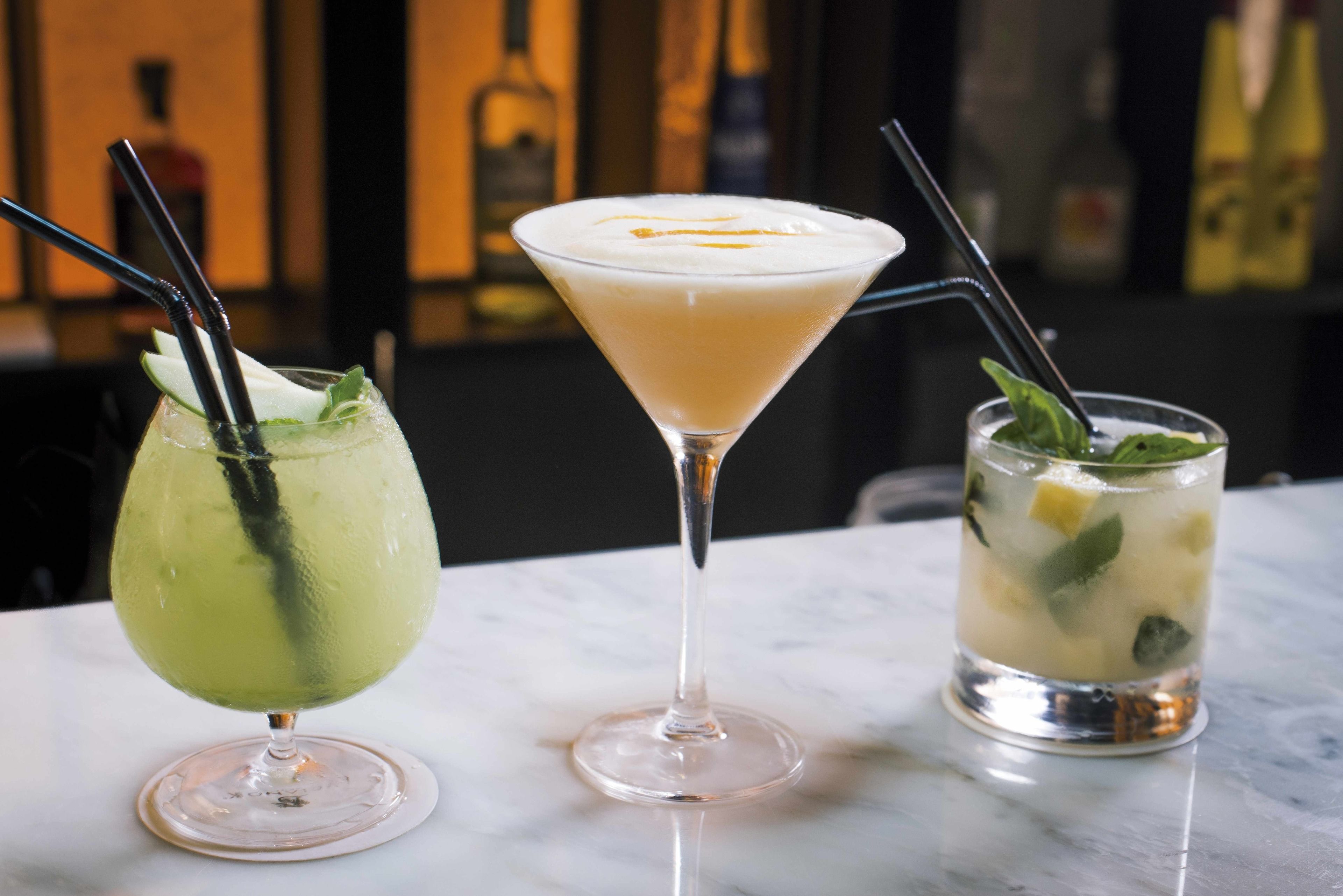 Drei verschiedene Getränke in Martini-Gläsern auf einer Marmorplatte.
