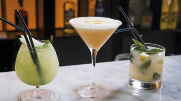Three different types of drinks in martini glasses on a marble surface.