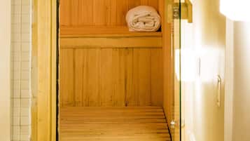 A wooden sauna with a bench and shelves for towels.