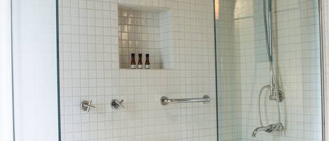A modern bathroom with a glass-enclosed shower, a white tiled wall, and a wooden panel design on the lower half.