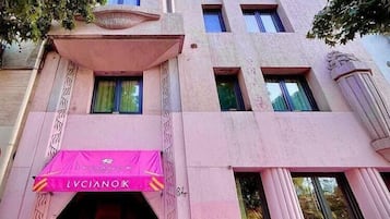 Un edificio de fachada rosa, con una entrada visible y un toldo rosa, y el número 8 en la parte lateral.
