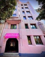 Un edificio de fachada rosa, con una entrada visible y un toldo rosa, y el número 8 en la parte lateral.