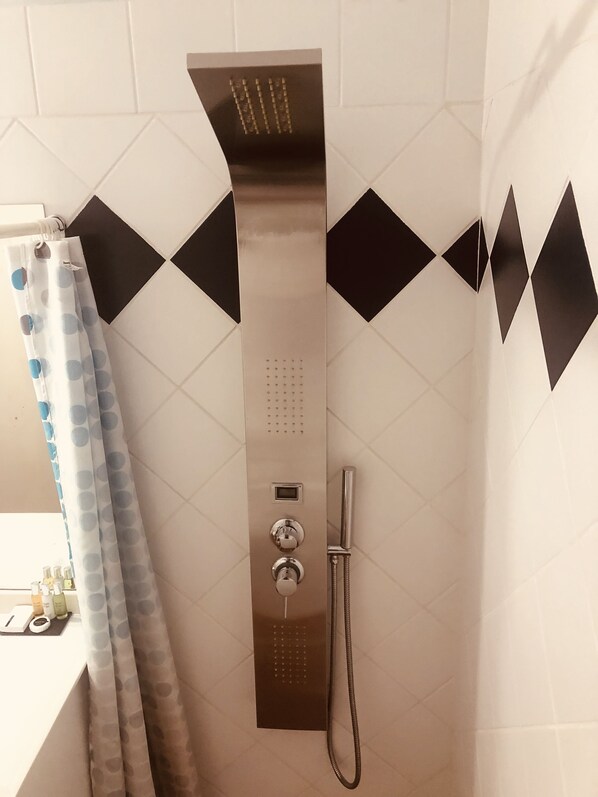 A shower area with a control panel, a handheld showerhead, and a curtain. - Karibu Aruba Boutique Hotel (Noord)