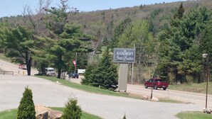 A sign for Bancroft Inn & Suites with a view of a road, trees, and a hilly landscape in the background.