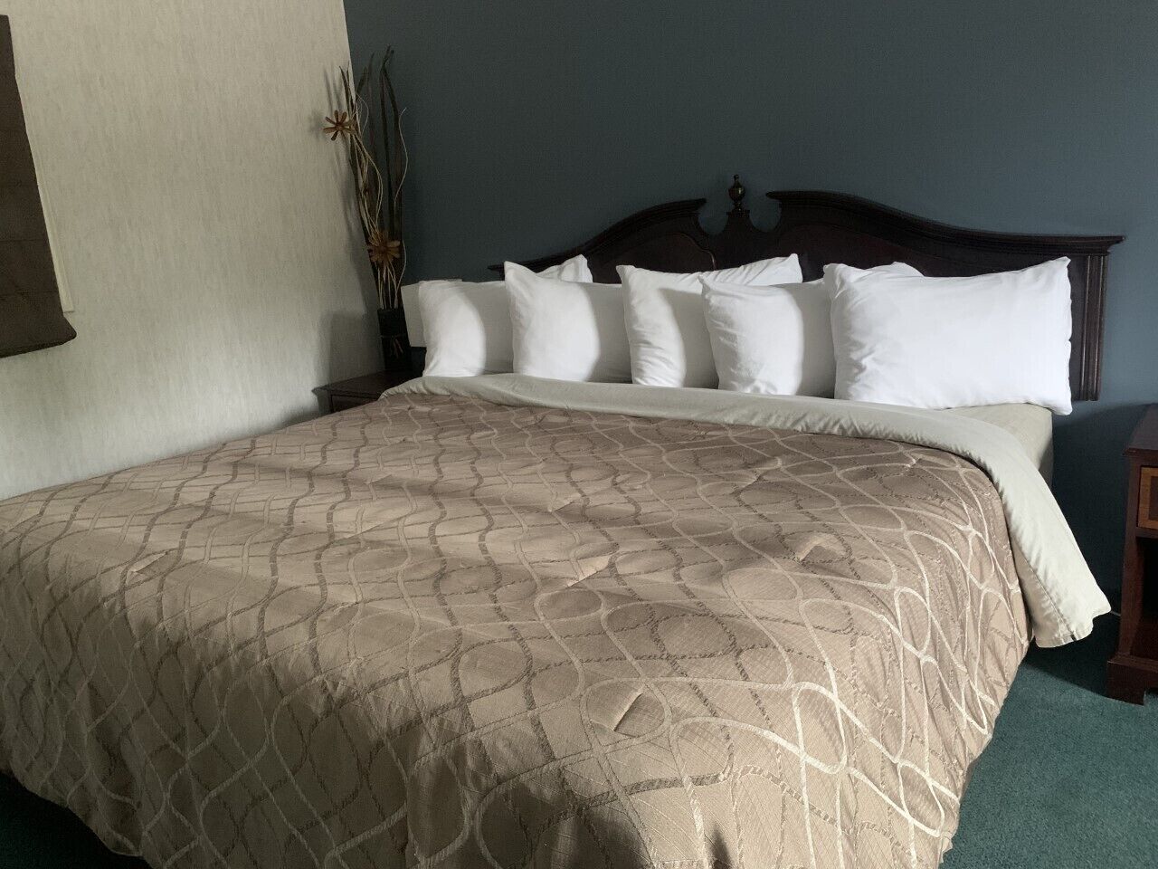 A neatly made bed with a patterned bedspread and multiple pillows.