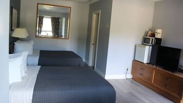 A hotel room with a bed, a dresser, a television, and a microwave.