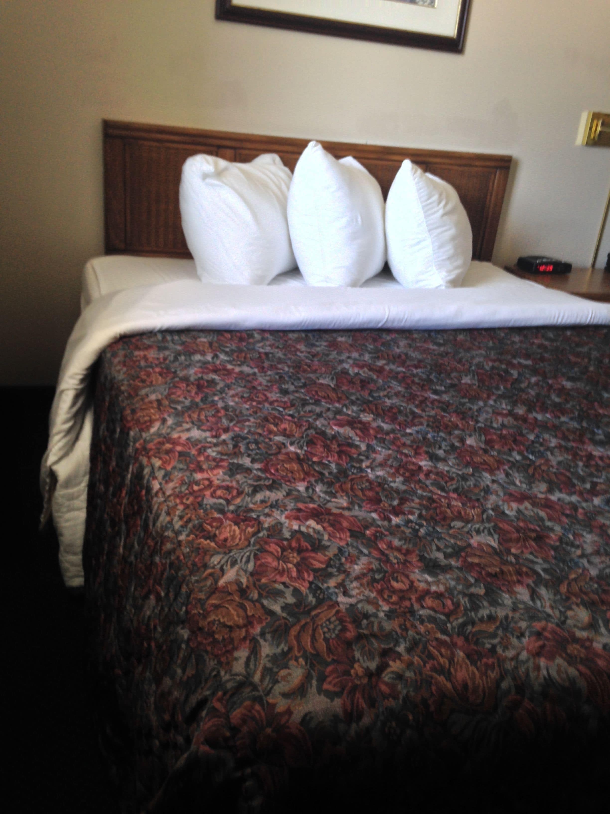 A neatly made bed with a floral bedspread and white pillows.